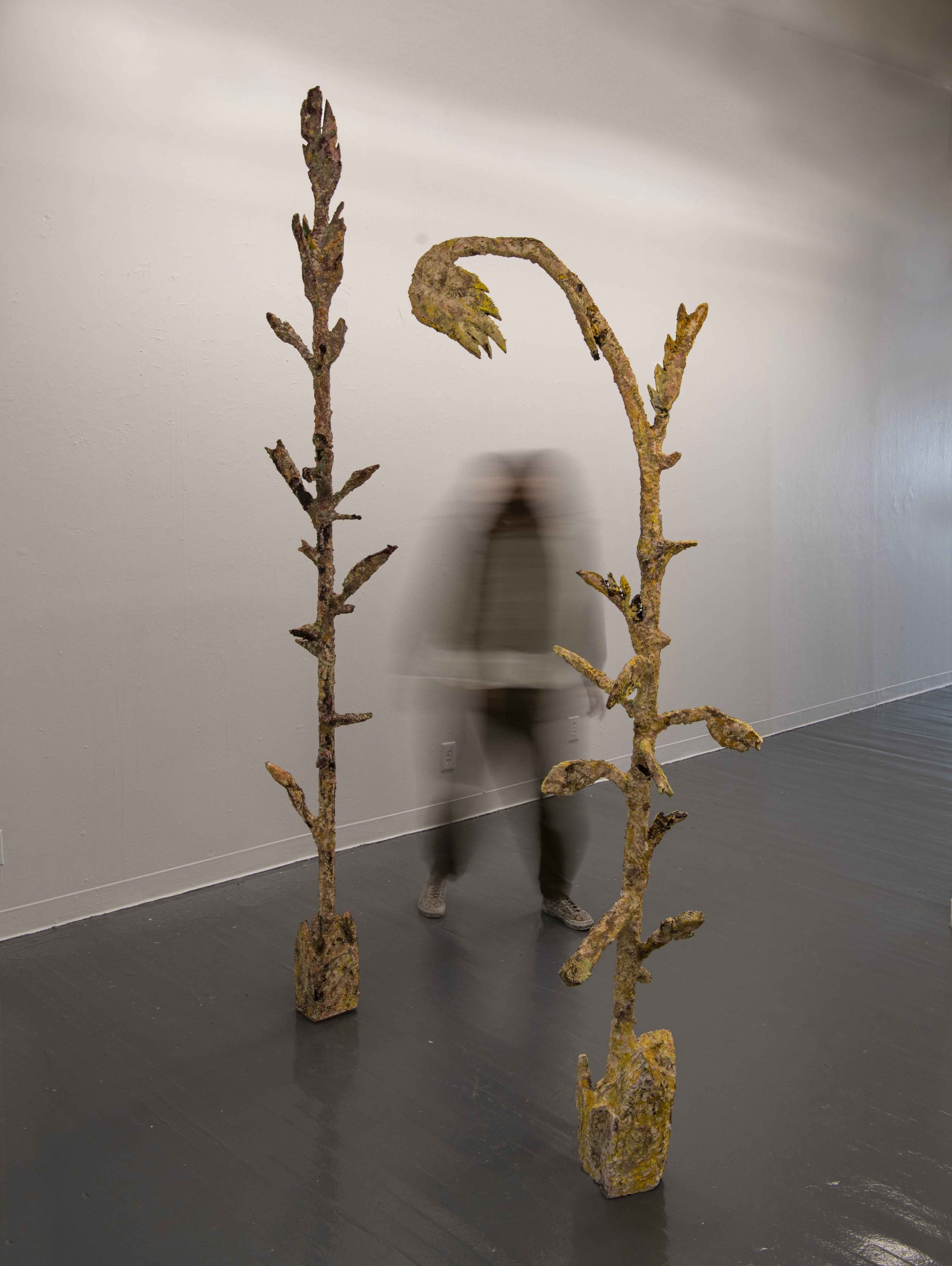 two tall sculptures in the shape of reeds, one person is in between them.